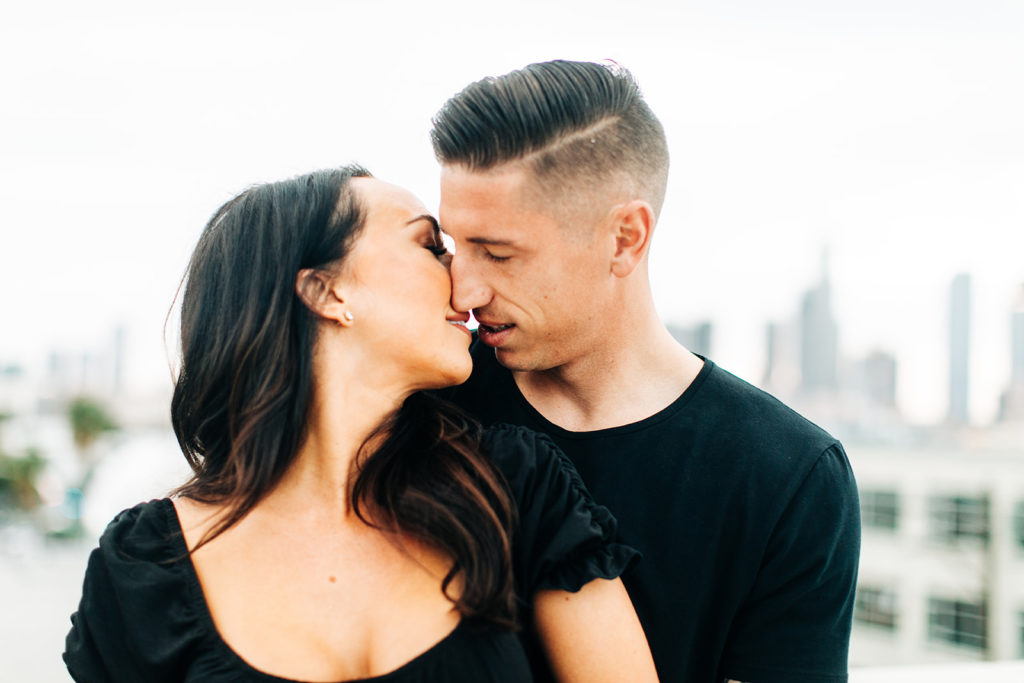 rooftop engagement photos in los angeles; a couple about to kiss on a rooftop with buildings in the background in los angeles, ca