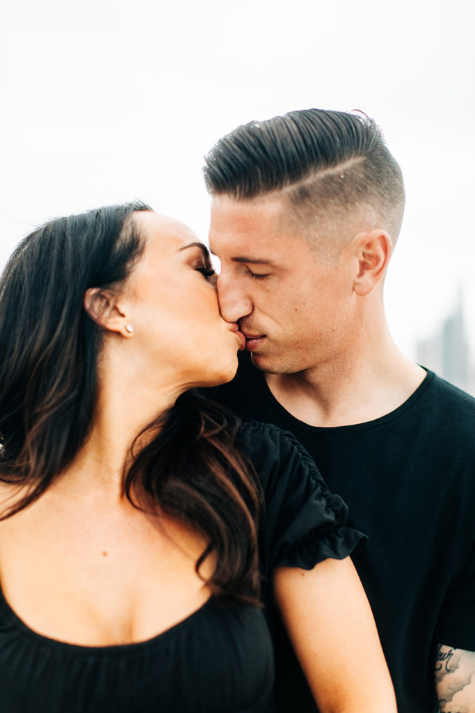 rooftop engagement photos in los angeles; a couple kissing on a rooftop with buildings in the background in los angeles, ca