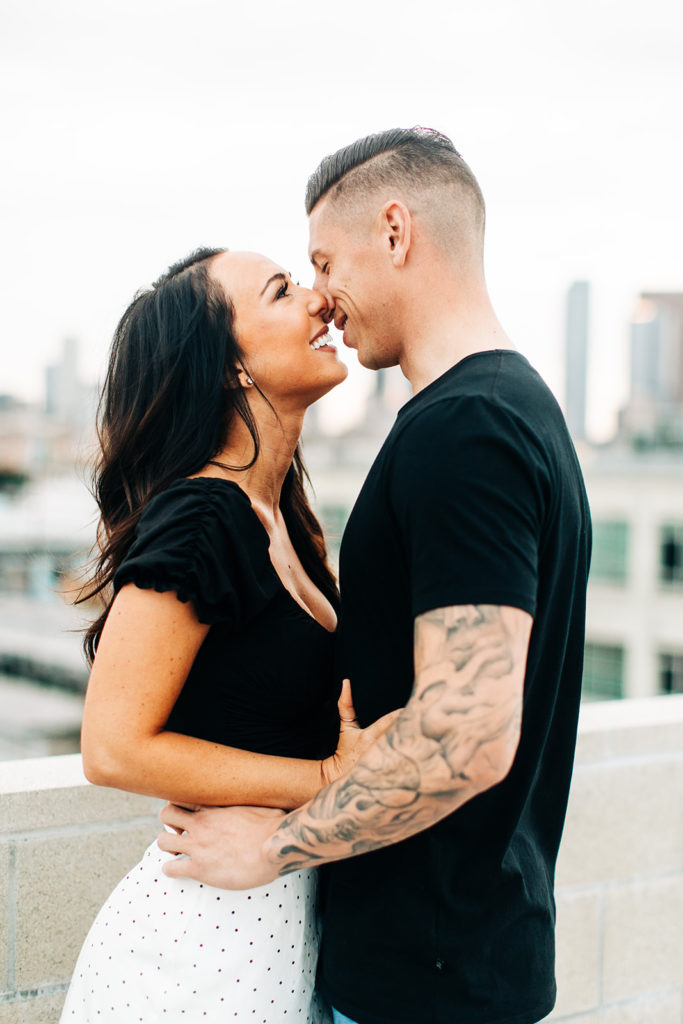 rooftop engagement photos in los angeles; a couple about to kiss on a rooftop with buildings in the background in los angeles, ca