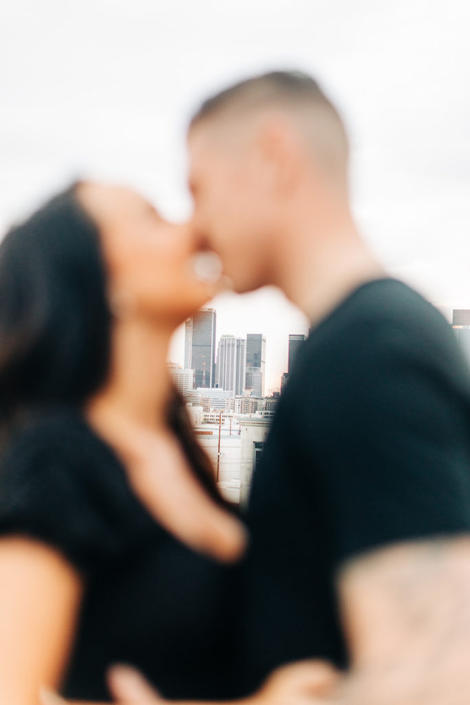 rooftop engagement photos in los angeles; a blurred couple about to kiss on a rooftop with buildings in the background in los angeles, ca
