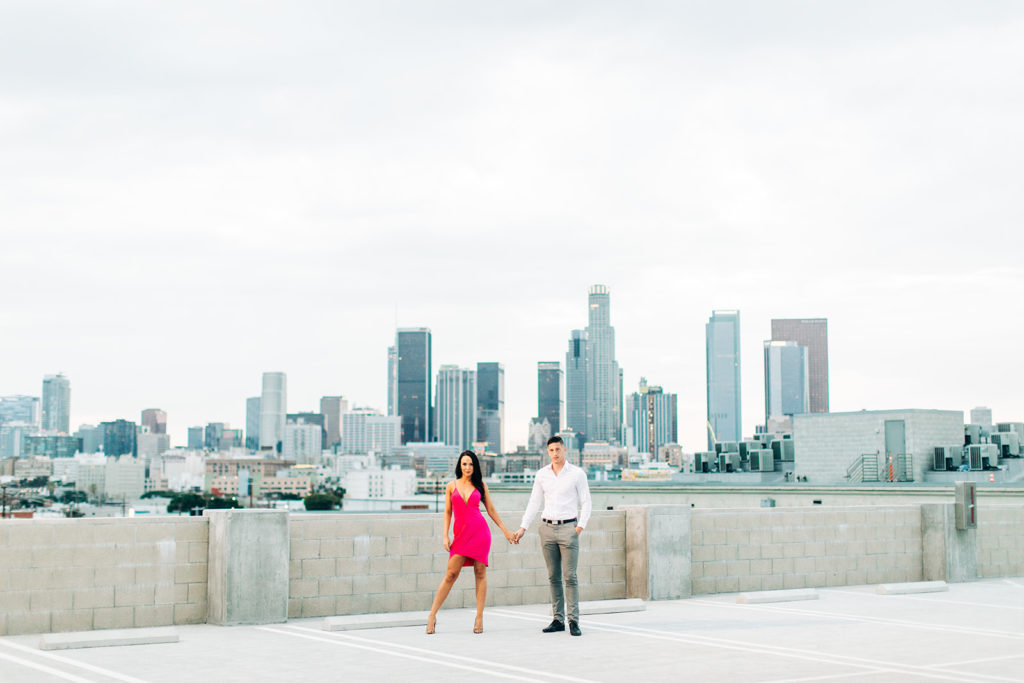 rooftop engagement photos in los angeles; a couple in formal outfits on a rooftop with buildings in the background in los angeles, ca