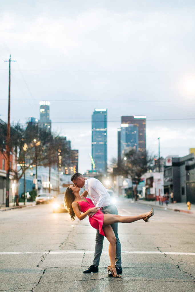 engagement photos in los angeles; a couple kissing in the middle of a busy street at night in los angeles, ca