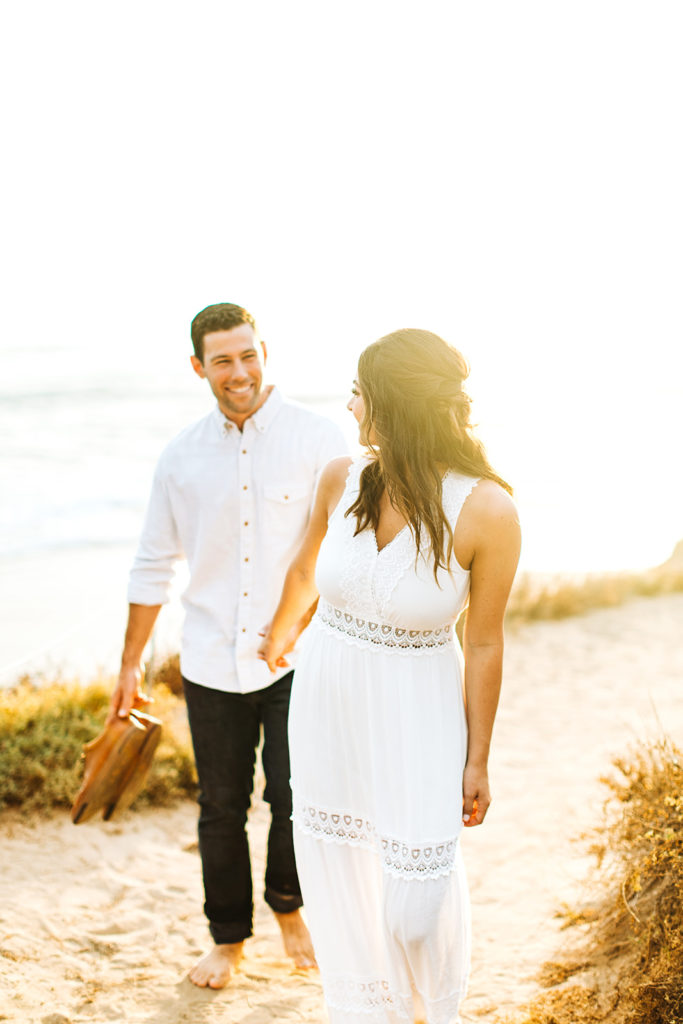southern california engagement photos; couple walking in the sunlight on the beach