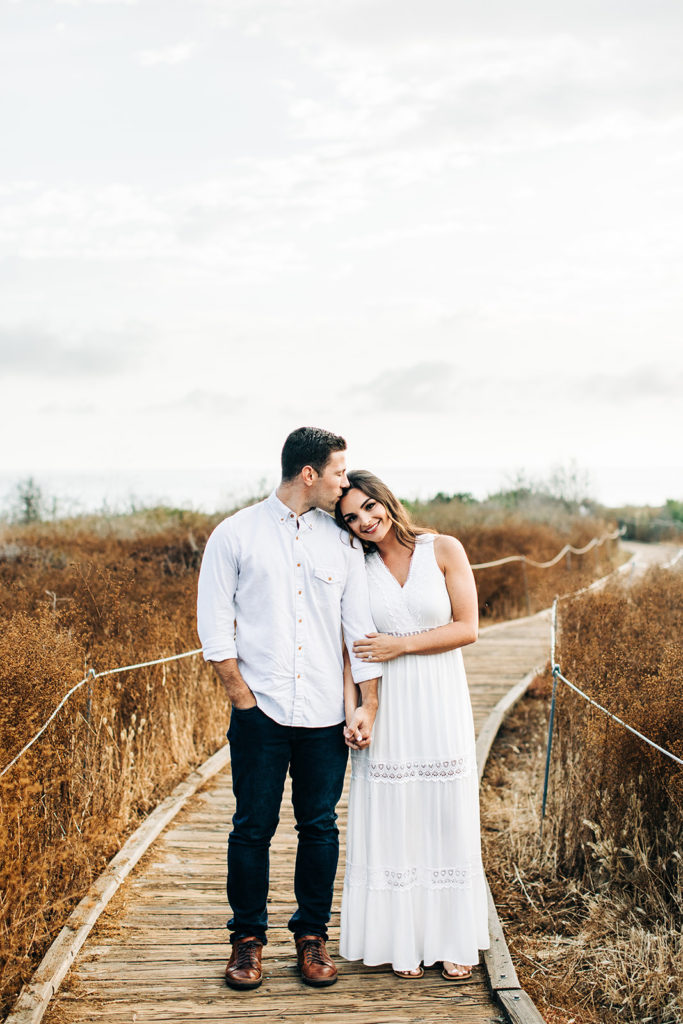 southern california engagement photos locations; couple embracing on the beach at crystal cove