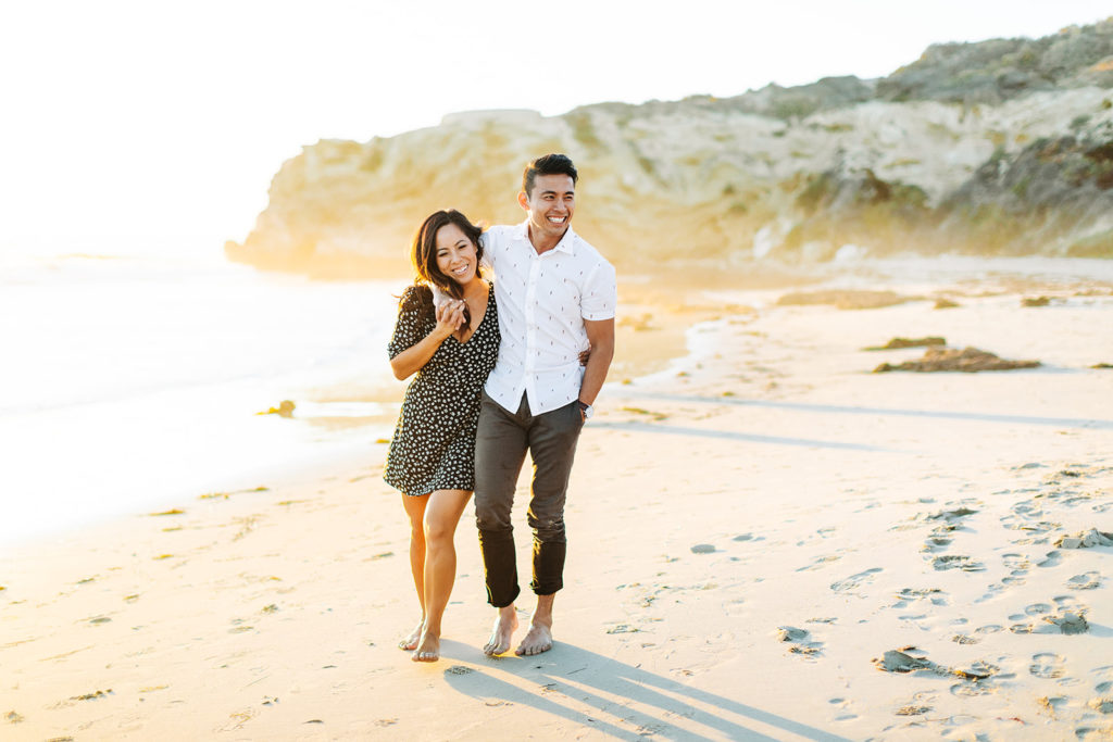 southern california engagement photos; couple walking in the sunlight on the beach