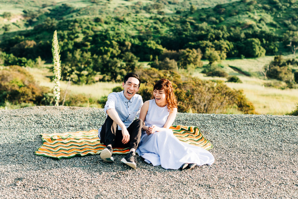 southern california engagement photos; couple sitting on a blanket and laughing