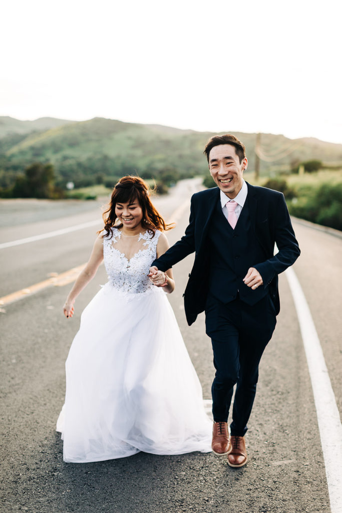 southern california engagement photos; couple in wedding attire running in the street and smiling