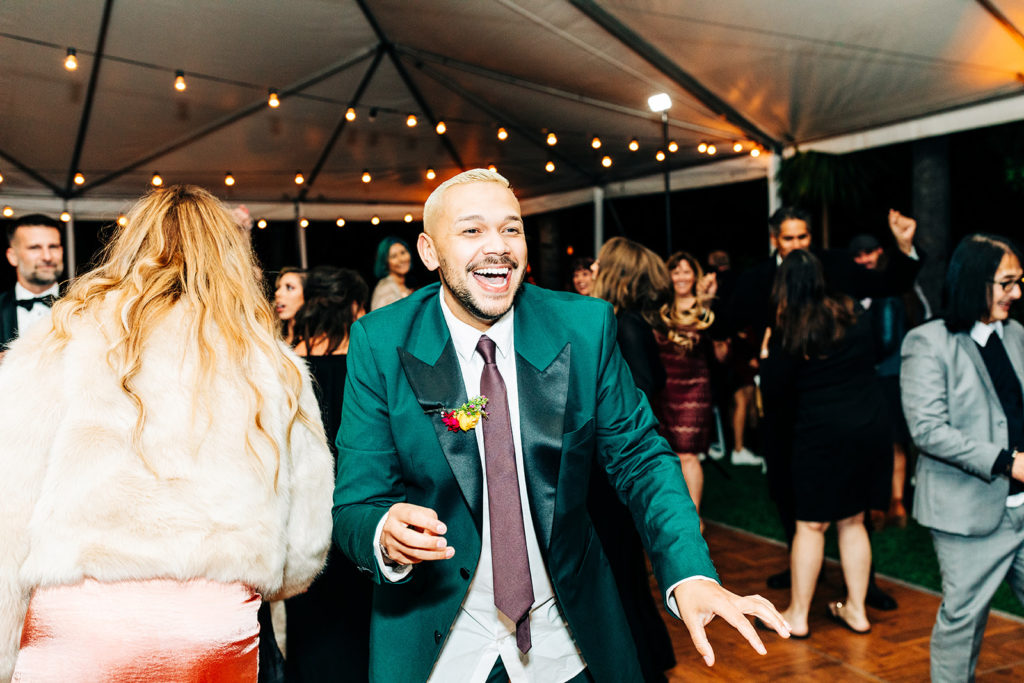 Hartley Botanica wedding photography; wedding guest in turquoise jacket laughing on dance floor