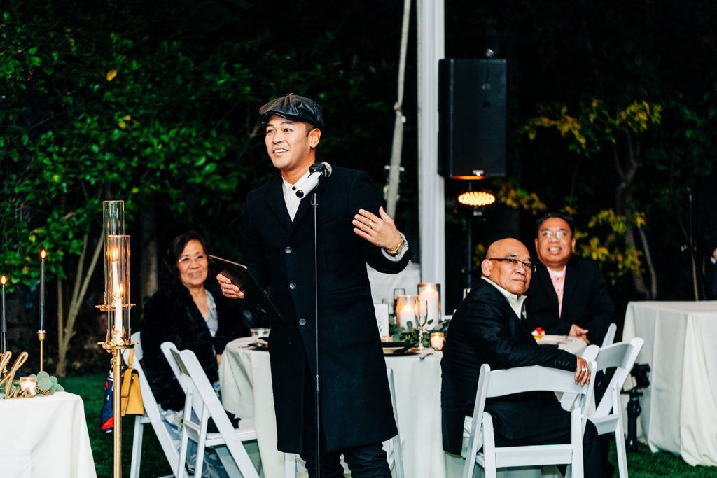Hartley Botanica wedding photography; best man in trench coat and Newsboy hat gives speech