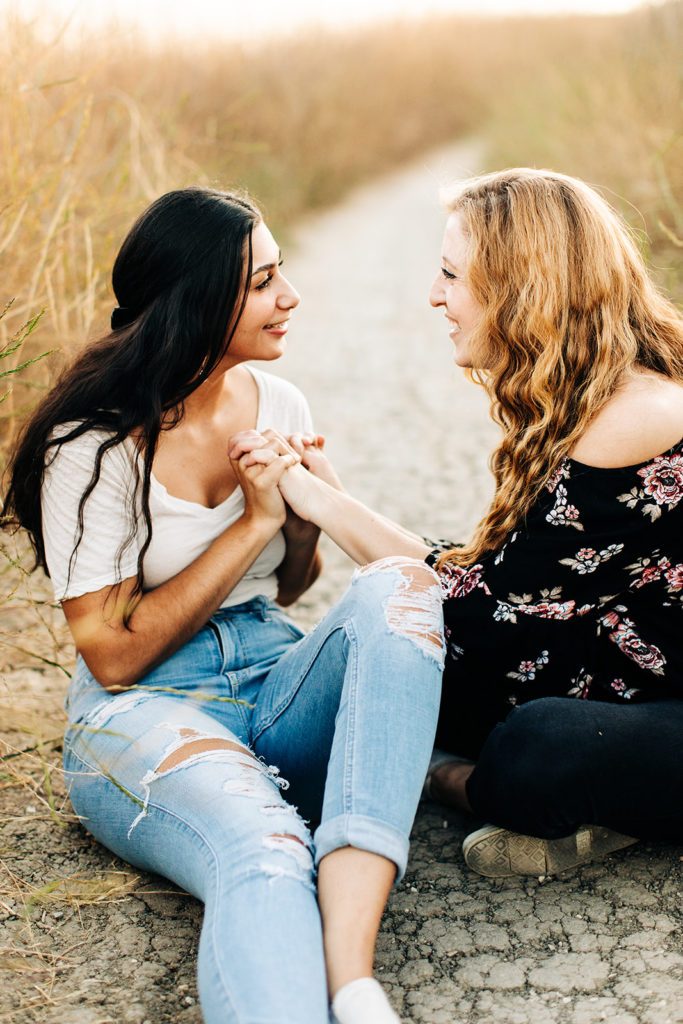 LGBTQ+ wedding photographer; two women sitting on the ground laughing at each other