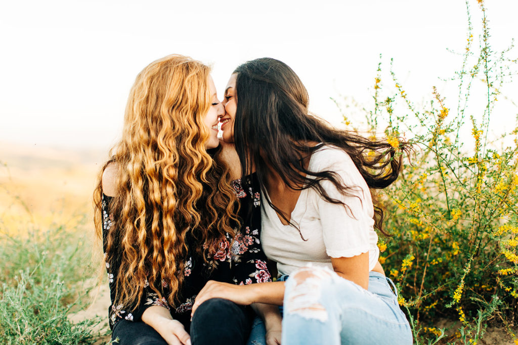 LGBTQ+ wedding photographer; two women smiling at each other about to kiss while sitting down