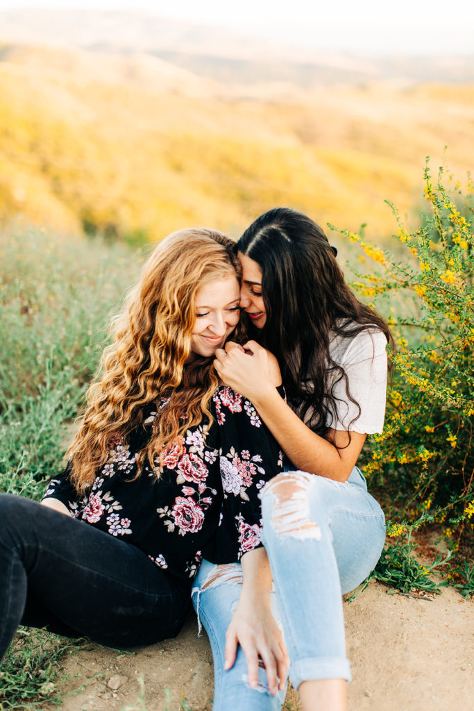 LGBTQ+ wedding photographer; a woman sitting in the lap of her girlfriend