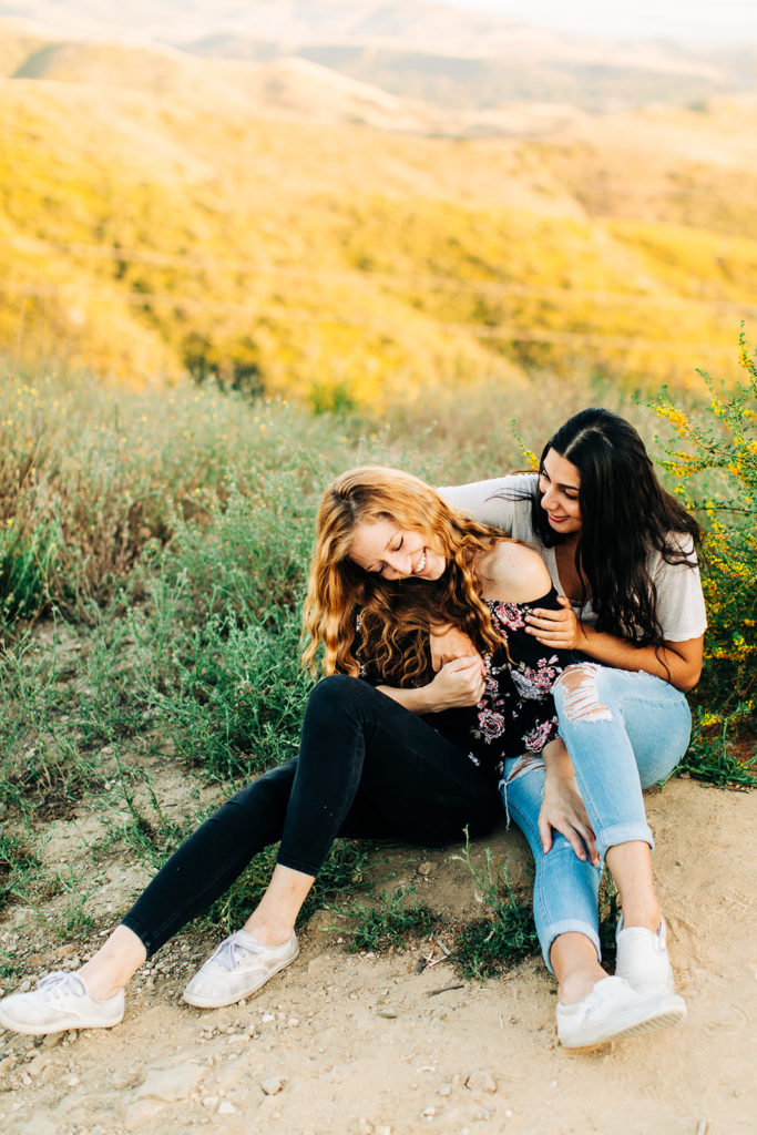 LGBTQ+ wedding photographer; two women playfully holding each other while laughing
