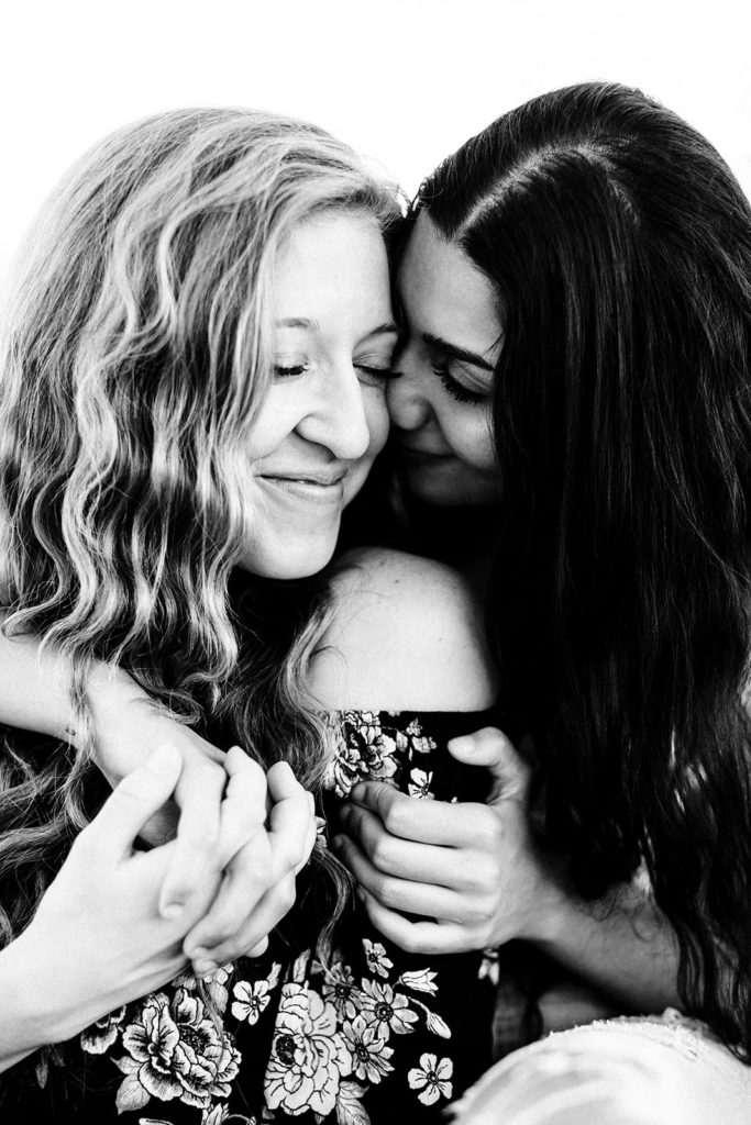 LGBTQ+ wedding photographer; a closeup black and white image of a woman lovingly embracing her girlfriend