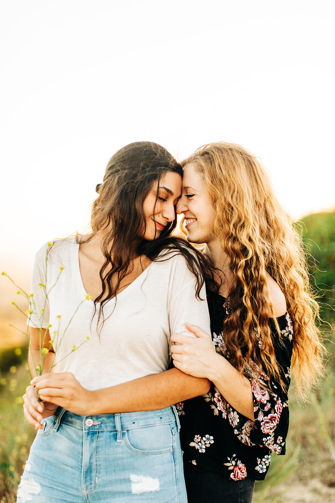 LGBTQ+ wedding photographer; two women embracing each other lovingly while holding wildflowers