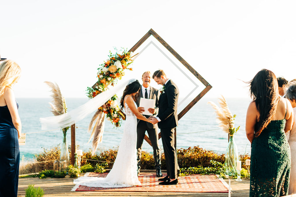 Crystal Cove Micro Wedding in Orange County; bride and groom and their officiant praying at their wedding