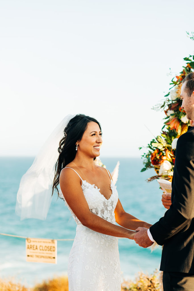 Crystal Cove Micro Wedding in Orange County; bride holding hands with the groom at their wedding