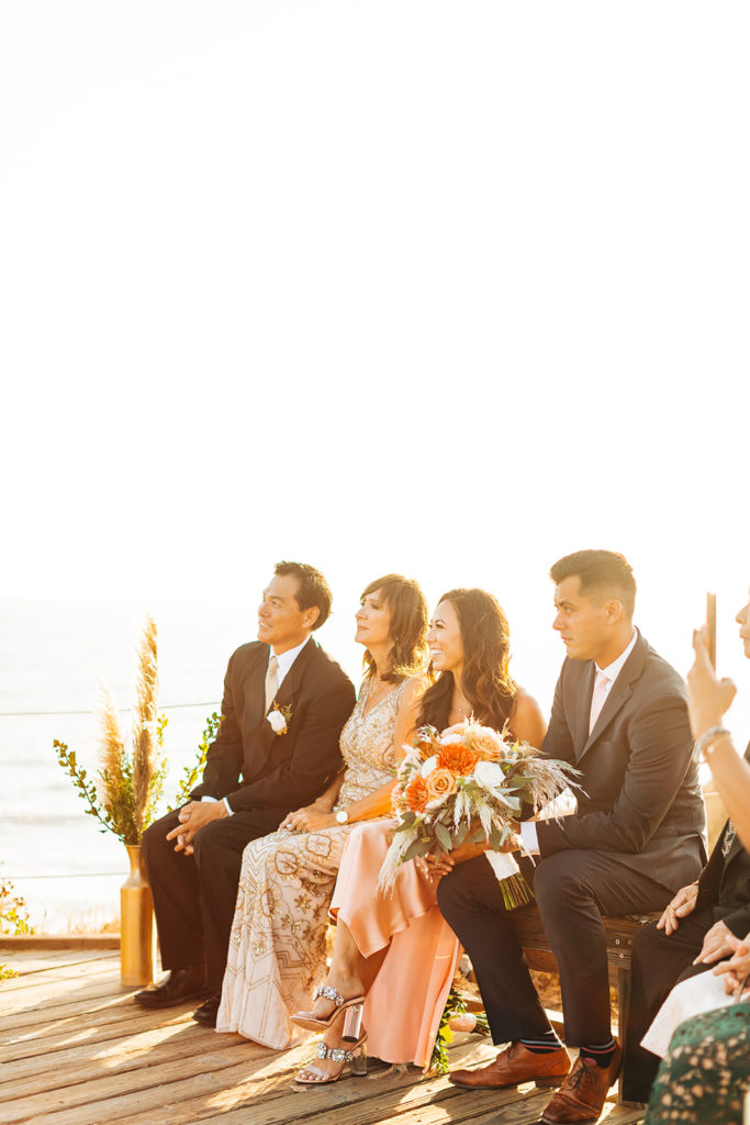 Crystal Cove Micro Wedding in Orange County; family listening to the ceremony at a micro wedding by the beach in orange county, california