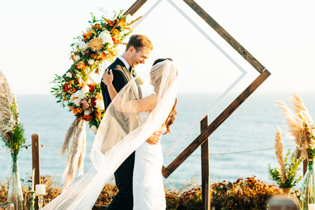 Crystal Cove Micro Wedding in Orange County; bride's veil is flowing as the couple dances at their wedding