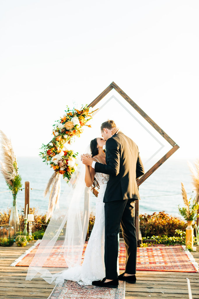 Crystal Cove Micro Wedding in Orange County; bride and groom kiss during their first dance at their wedding