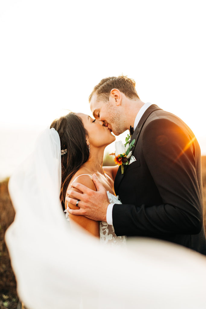 Crystal Cove Micro Wedding in Orange County; bride and groom kissing while the bride's veil flows
