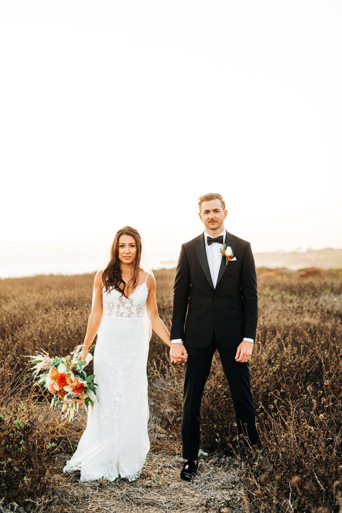 Crystal Cove Micro Wedding in Orange County; bride and groom holding hands and looking seriously at the camera