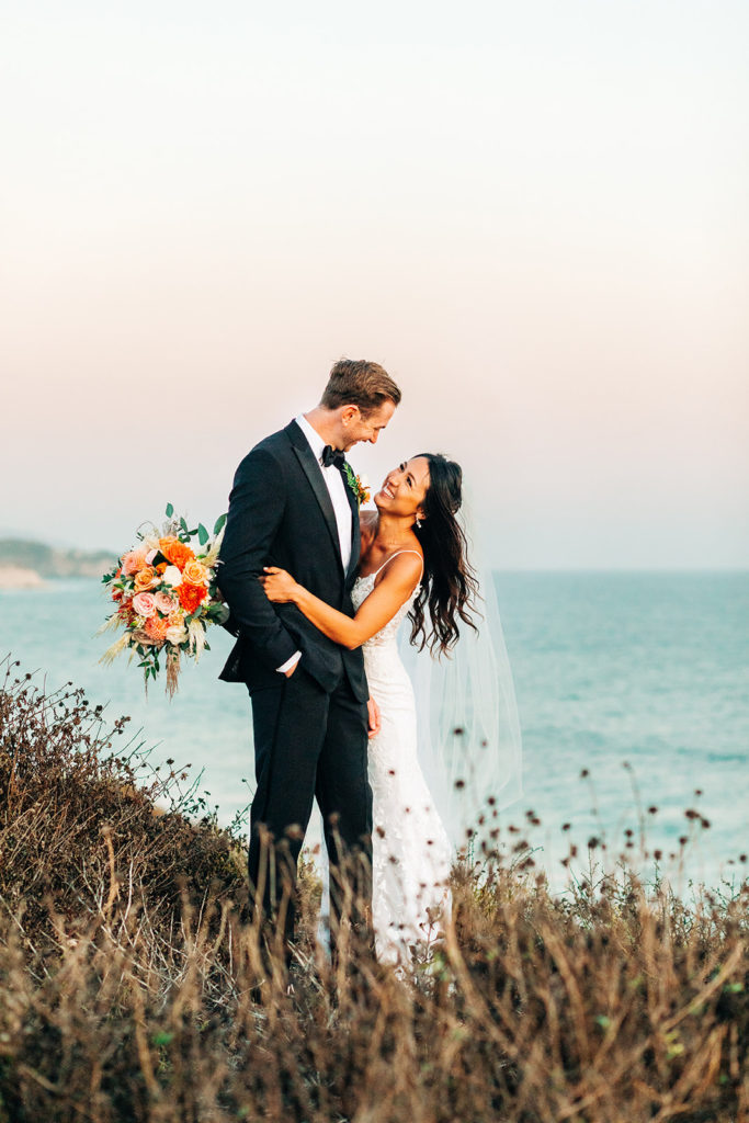 Crystal Cove Micro Wedding in Orange County; beautiful sunset behind a bride and groom hugging on their wedding day in orange county, california