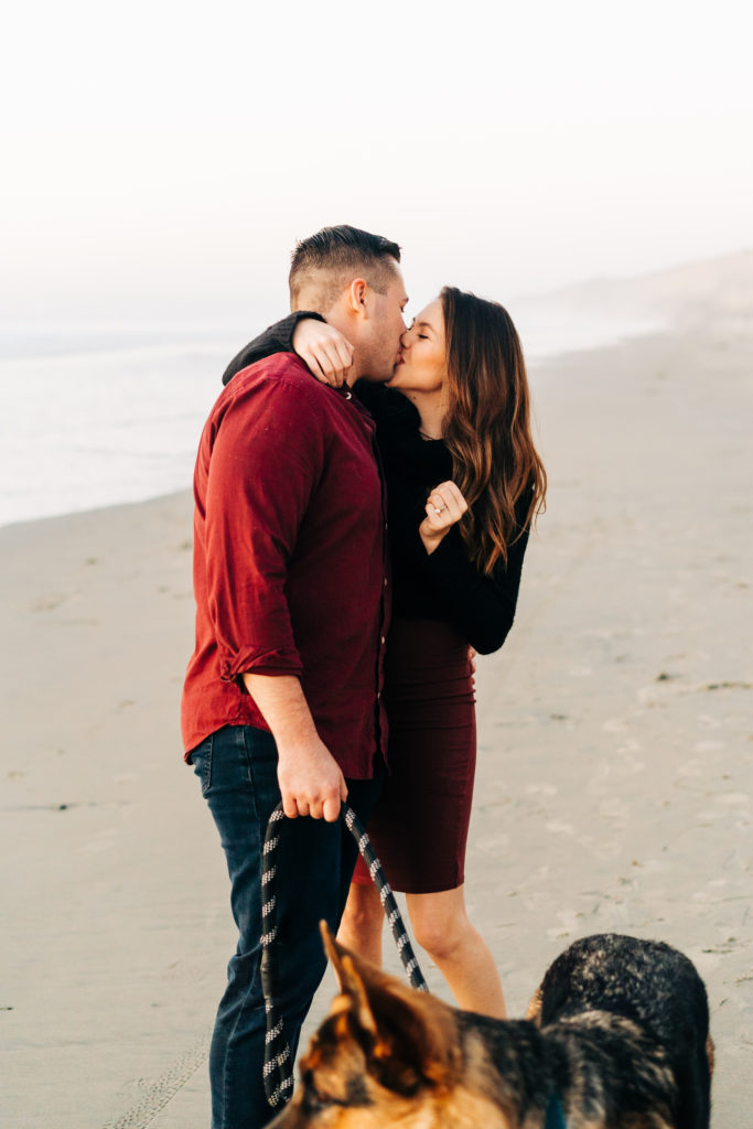 black's beach engagement photos; san diego wedding photographer; a husband and wife kiss at the beach, their dog is with them