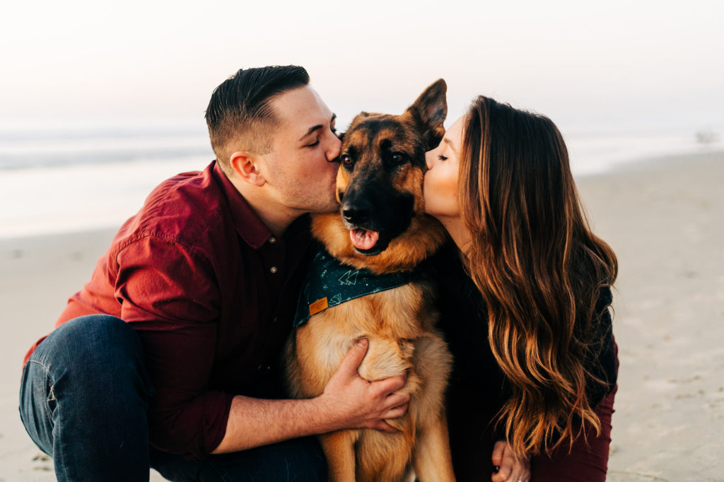 black's beach engagement photos; san diego wedding photographer; a couple kissing their dog, they dog's tongue is out, they are at the beach