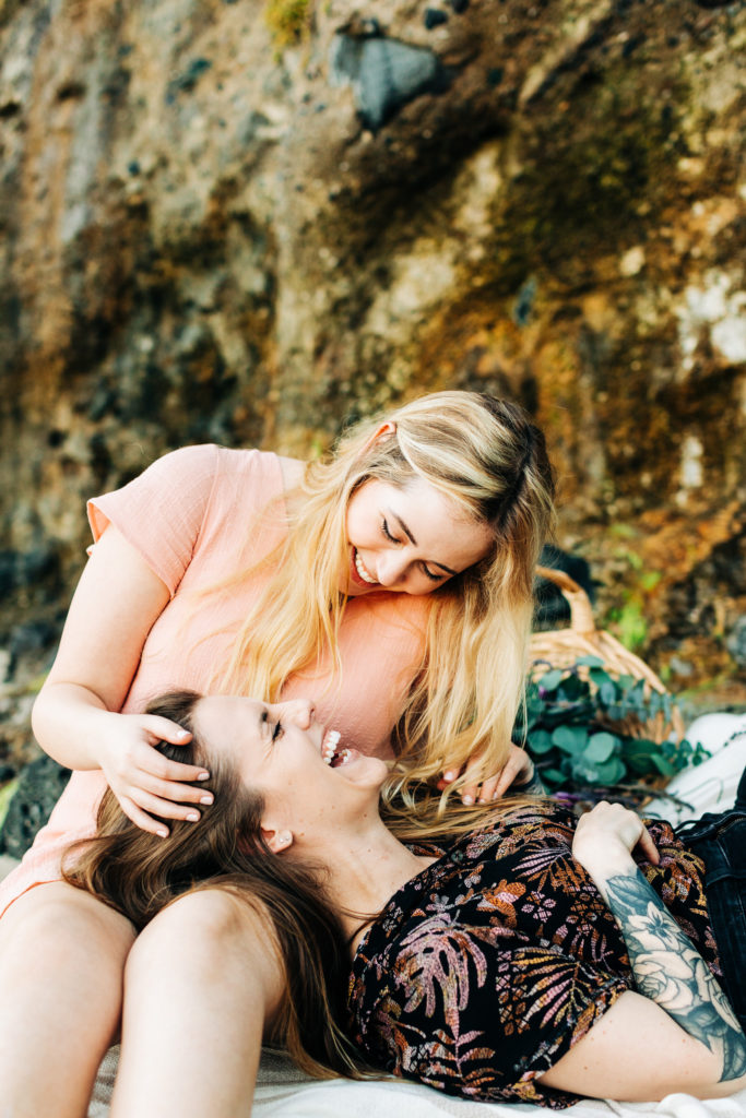 LGBTQ+ wedding photographer in san diego; a lesbian couple having a picnic at the beach, they are smiling at each other