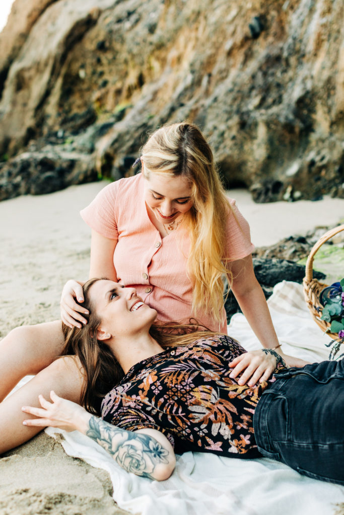 LGBTQ+ wedding photographer in san diego; a lesbian couple having a picnic at the beach, one is laying in the other's lap