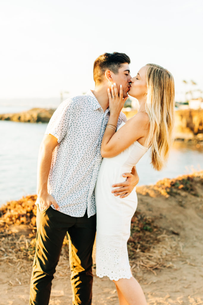 san diego engagement photos at sunset cliffs; san diego wedding photographer; a man and woman are kissing, the beach is in the background