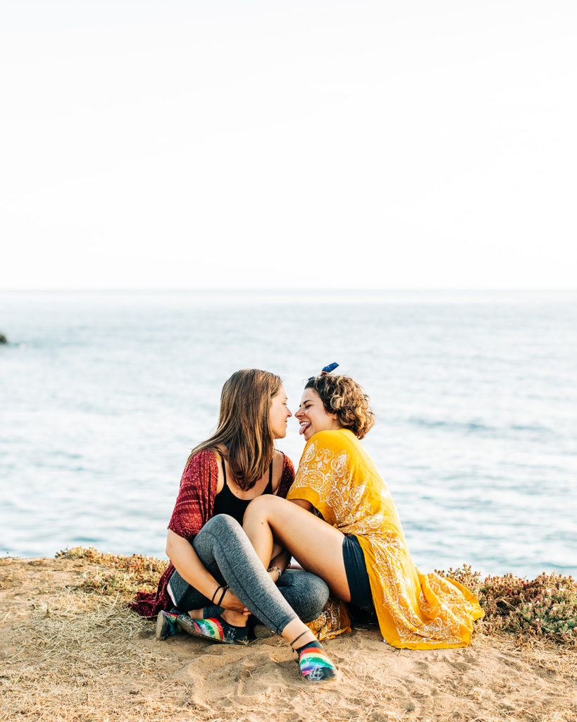 san diego wedding photographer; sunset cliffs engagement photos; two women about to kiss, they are sitting on a cliff overlooking the ocean in san diego, california