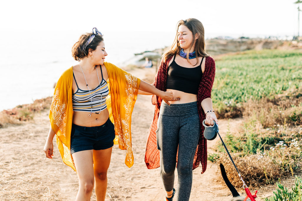 san diego wedding photographer; sunset cliffs engagement photos; two women walking together and joking around with each other