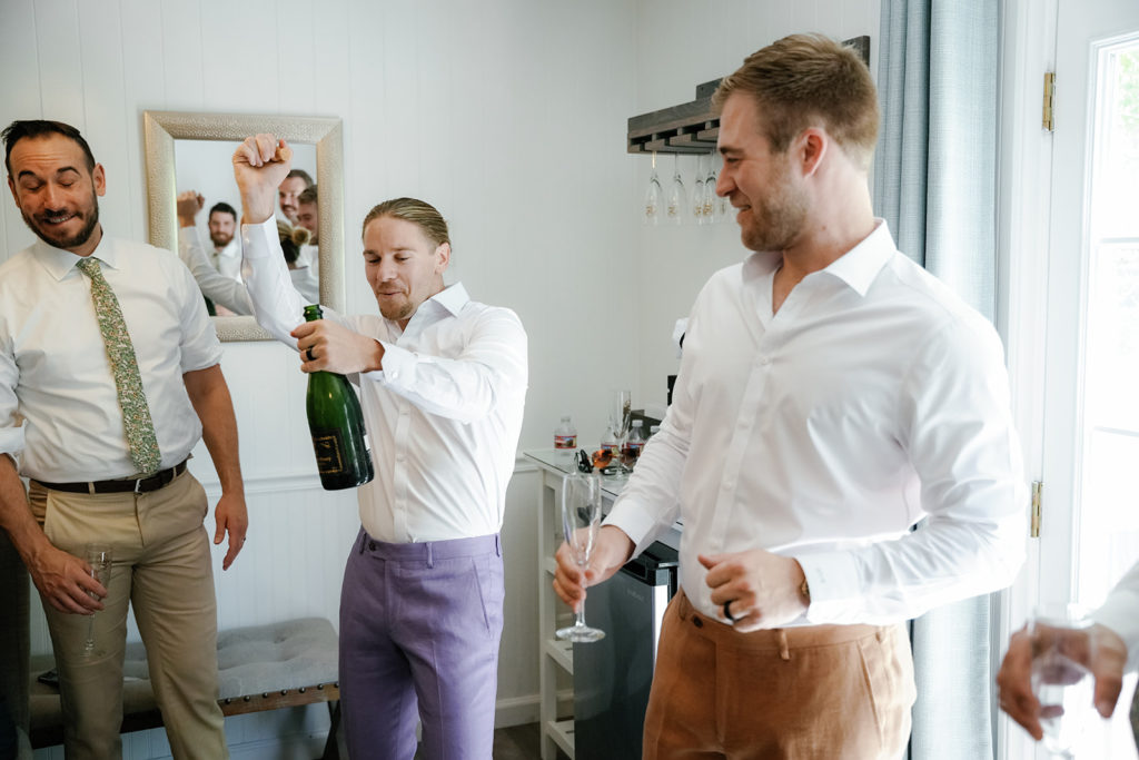 a groom pops champagne on his wedding day; gay wedding in temecula at mount palomar winery