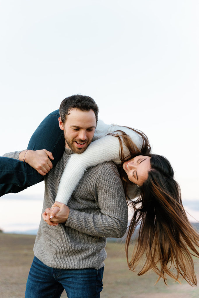 Romantic San Diego Engagement Photos; a man and woman smiling during their engagement photo session, the woman is on the man's back playfully.