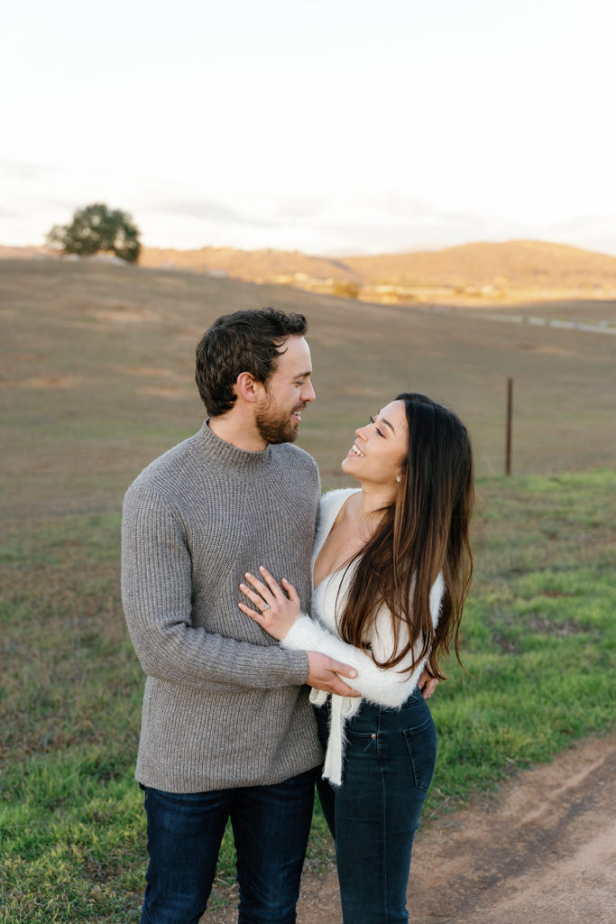 Romantic San Diego Engagement Photos; a man and woman smiling at each other during their engagement photo session.