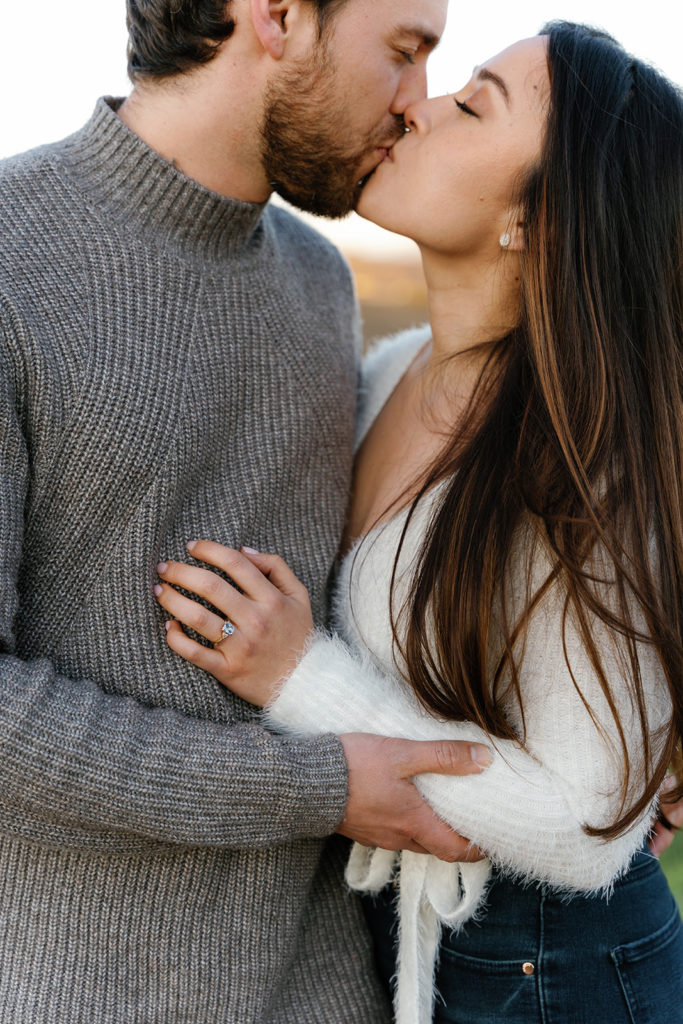 Romantic San Diego Engagement Photos; a man and woman kissing during their engagement photo session. The woman's ring is prominent!