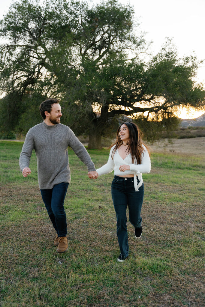 Romantic San Diego Engagement Photos; a man and woman running together during their engagement photo session.