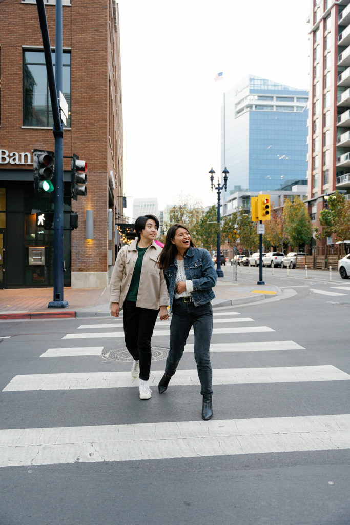 lgbtq photographer in san diego; two women holding hands during their engagement session in downtown san diego as they cross the street