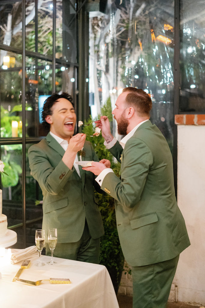 queer wedding photographer in san diego; two men feeding each other cake at their wedding