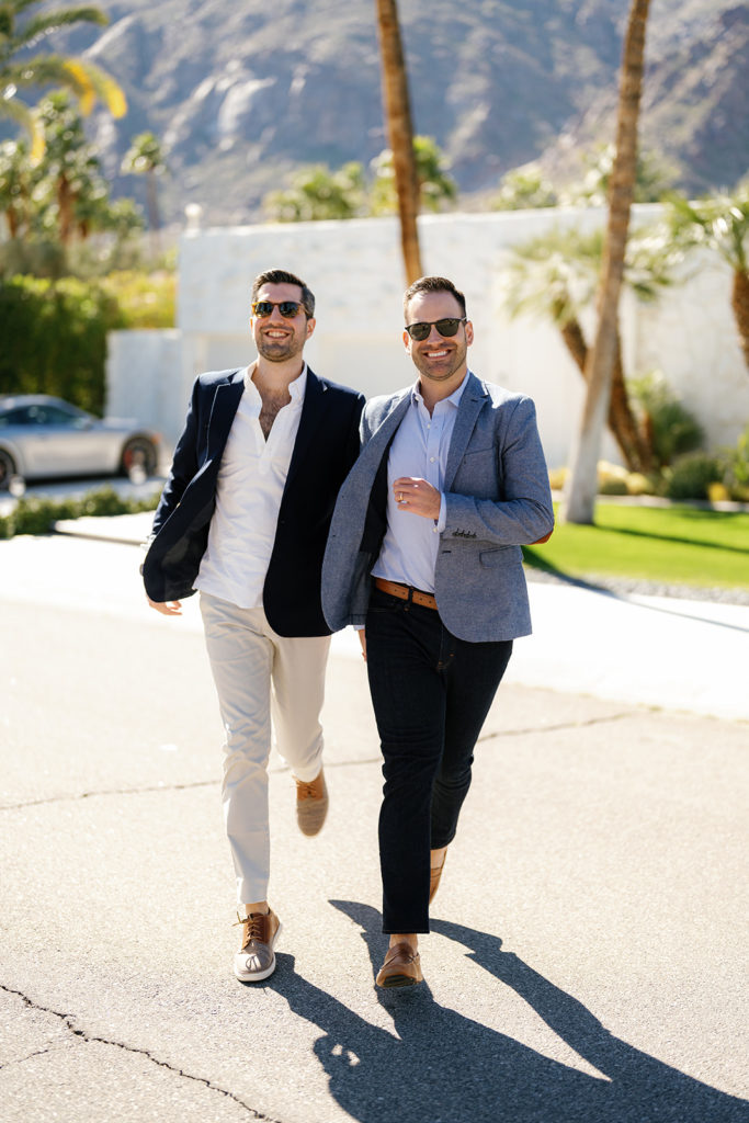 palm springs engagement photos; a gay couple running towards the camera and smiling