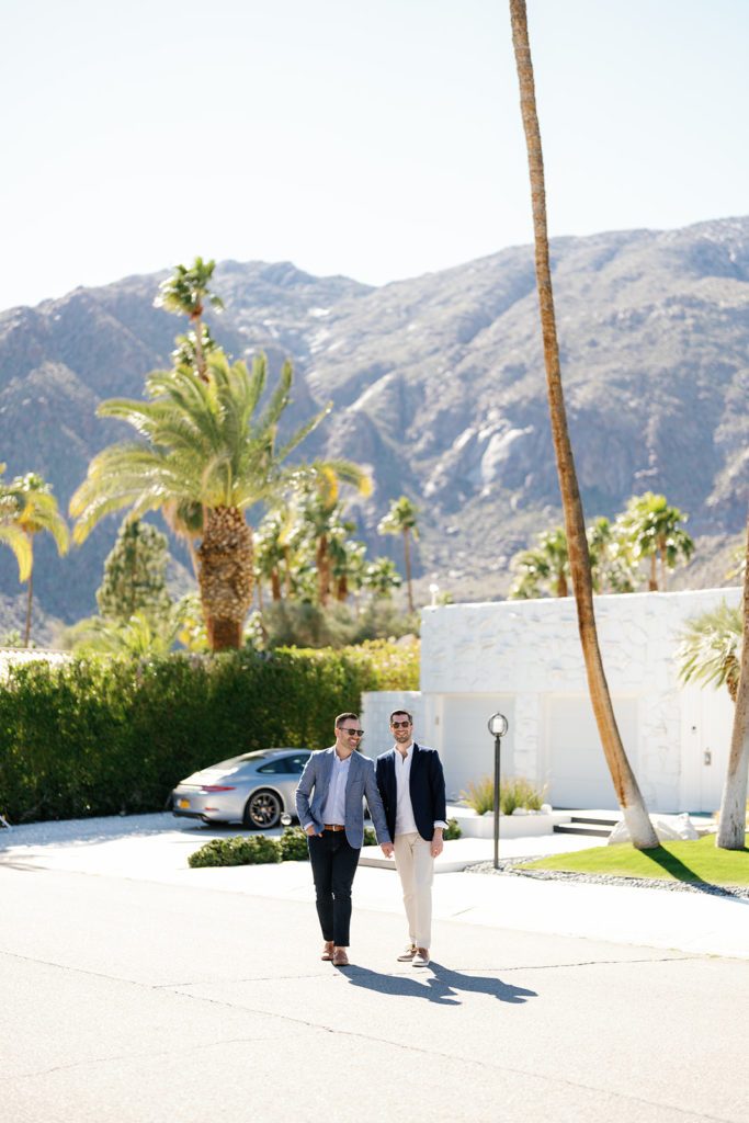 queer wedding photographer in san diego; two men holding hands and walking in palm springs during their engagement session