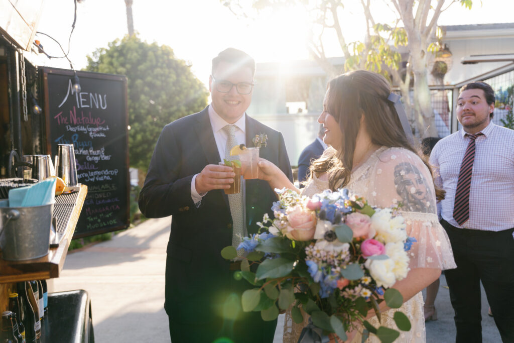 san diego micro wedding in solana beach; a couple with their drinks on their wedding day, they are cheers-ing